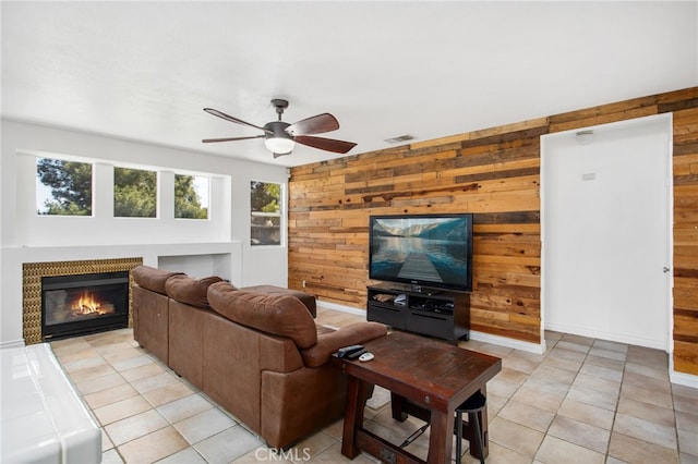 27304 Mystical Springs Dr, Corona, CA 92883 - living area featuring wooden walls, ceiling fan, light tile patterned flooring, and a glass covered fireplace
