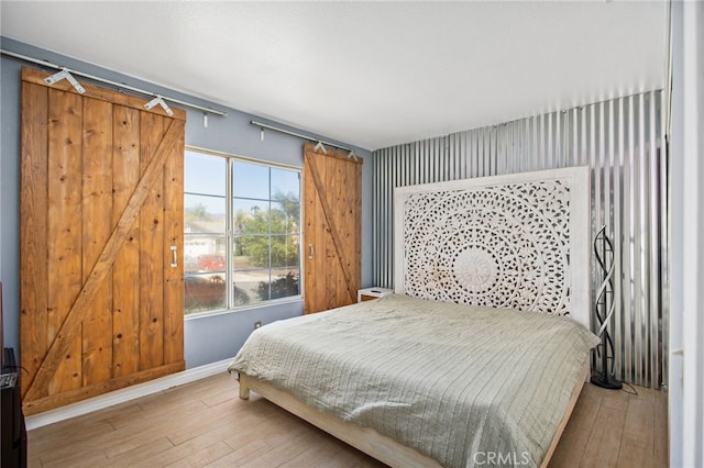 27304 Mystical Springs Dr, Corona, CA 92883 - bedroom featuring a barn door, hardwood / wood-style flooring, and baseboards