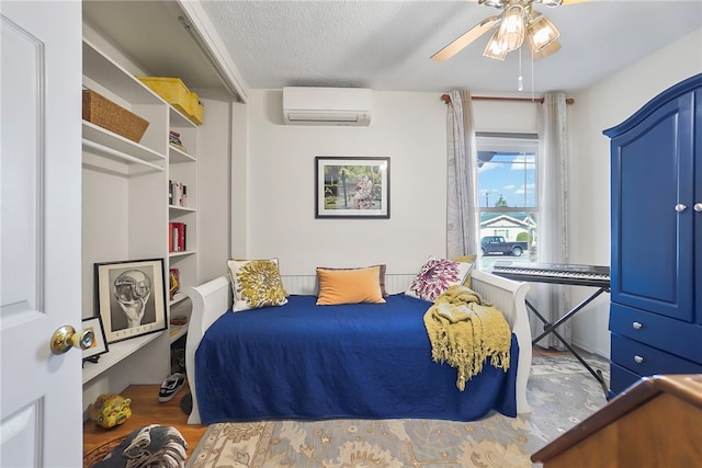 bedroom with a wall mounted air conditioner, a ceiling fan, wood finished floors, and a textured ceiling
