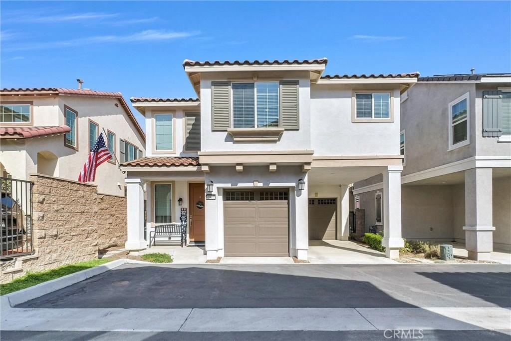 15186 Ridge Ln Unit 4, Fontana, CA 92336 - view of front of house featuring driveway, a tile roof, a garage, and stucco siding