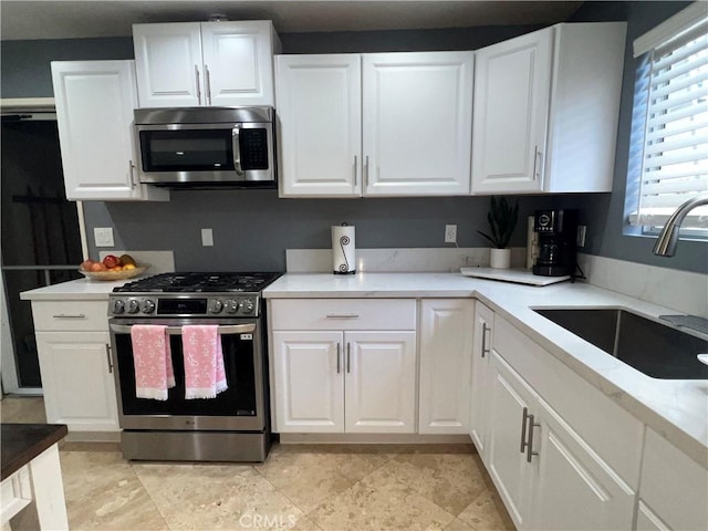 kitchen with a sink, light countertops, white cabinets, and appliances with stainless steel finishes