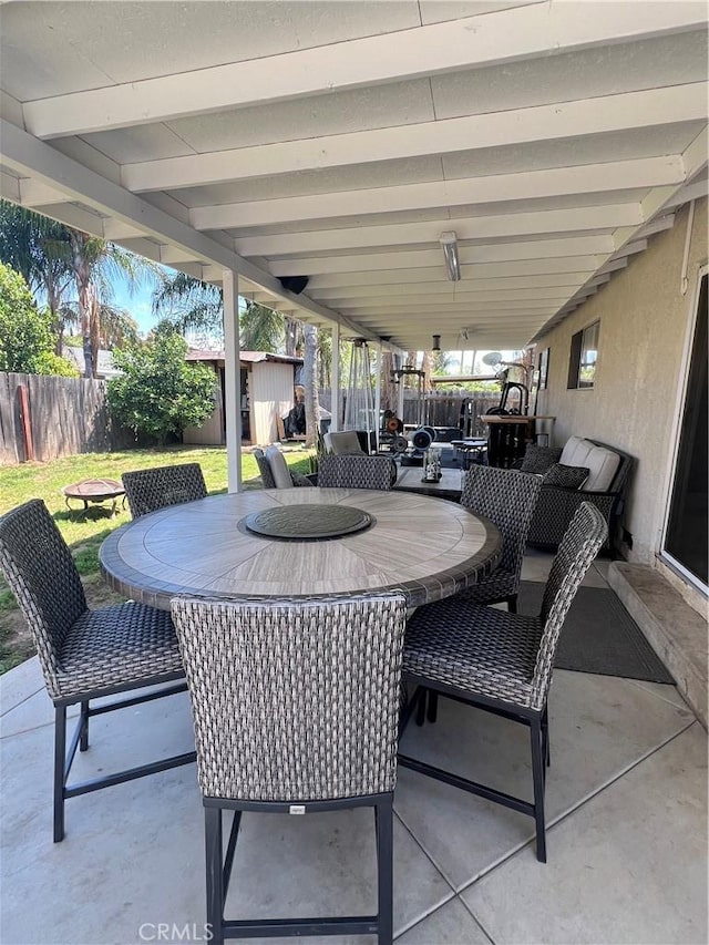 view of patio / terrace featuring an outbuilding, fence, and outdoor dining area
