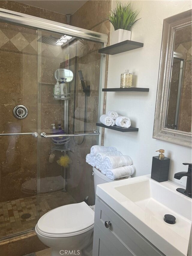 bathroom with toilet, a stall shower, and vanity