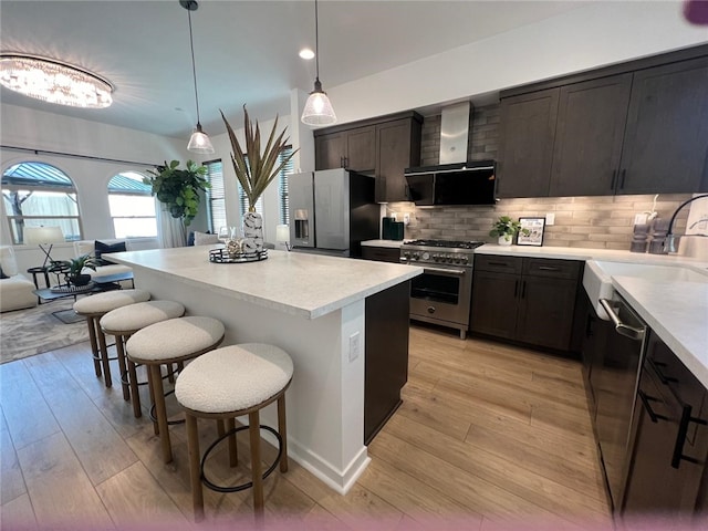 772 Francesca Dr, Walnut, CA 91789 - kitchen featuring appliances with stainless steel finishes, island exhaust hood, a kitchen bar, a center island, and light countertops