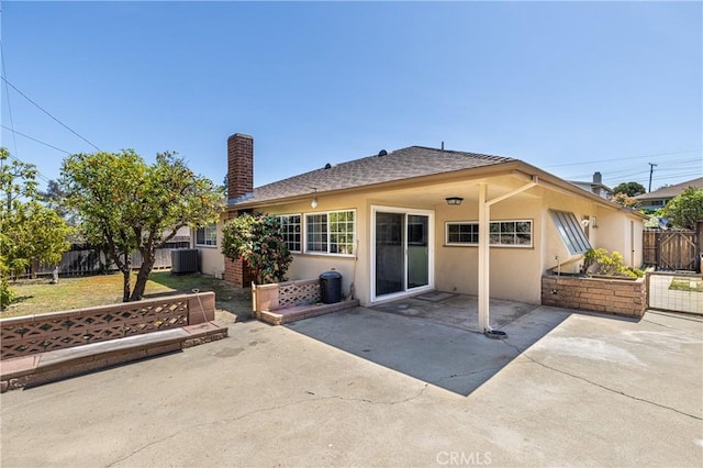 back of house featuring stucco siding, roof with shingles, a patio area, fence, and a chimney