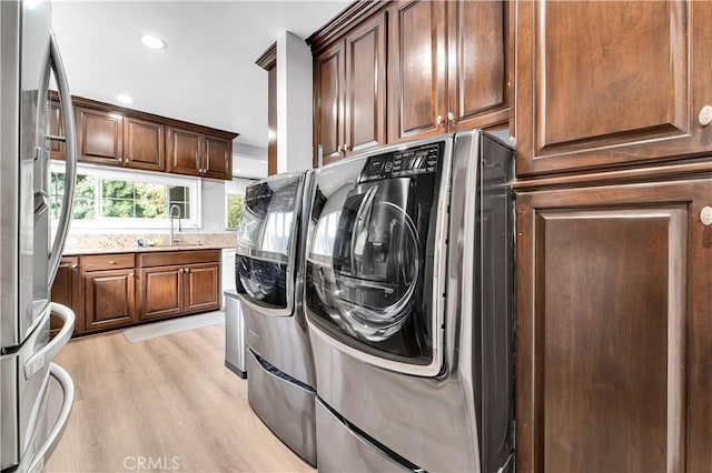 laundry room with recessed lighting, light wood-type flooring, a sink, and cabinet space
