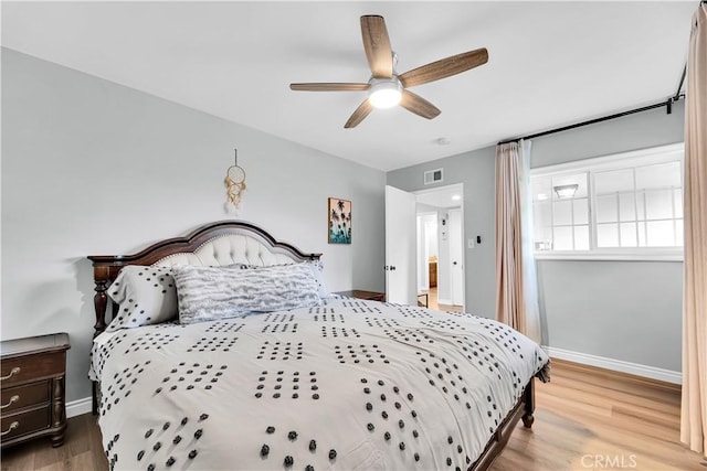 bedroom with wood finished floors, baseboards, a ceiling fan, and visible vents