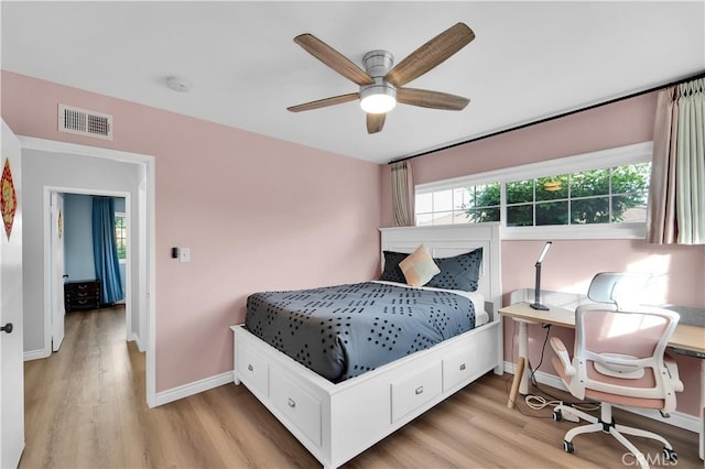 bedroom featuring light wood-type flooring, baseboards, a ceiling fan, and visible vents