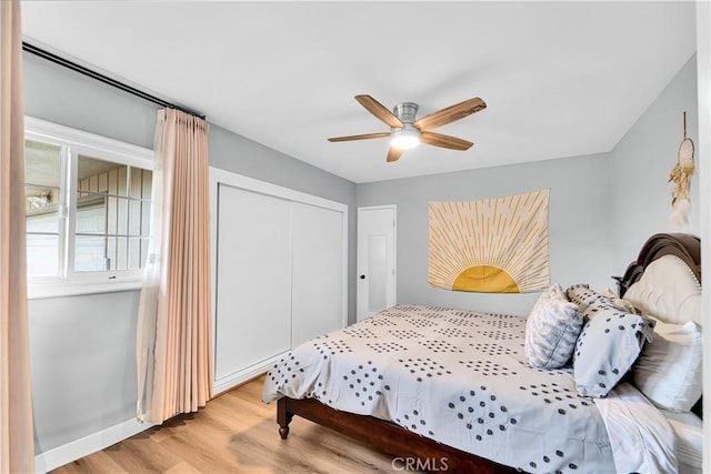 bedroom with ceiling fan, a closet, baseboards, and wood finished floors