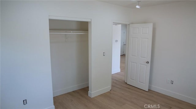 unfurnished bedroom featuring baseboards, a closet, and wood finished floors
