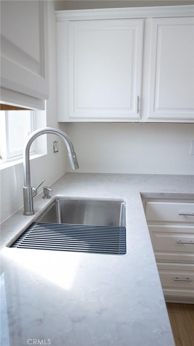 details with a sink, white cabinets, and light countertops