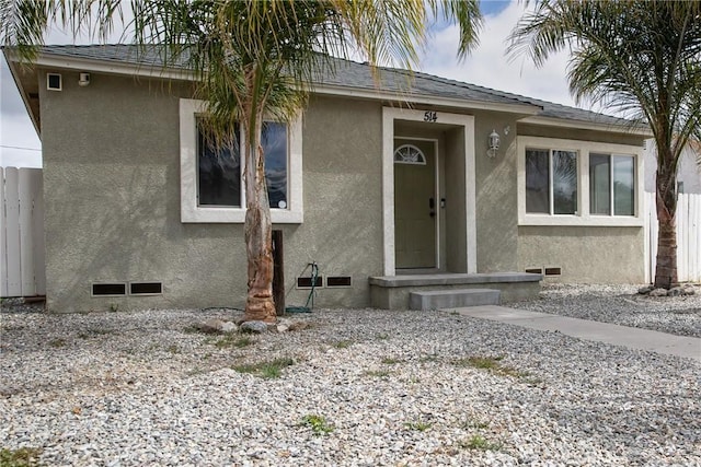 view of front of house featuring fence, stucco siding, a shingled roof, and crawl space
