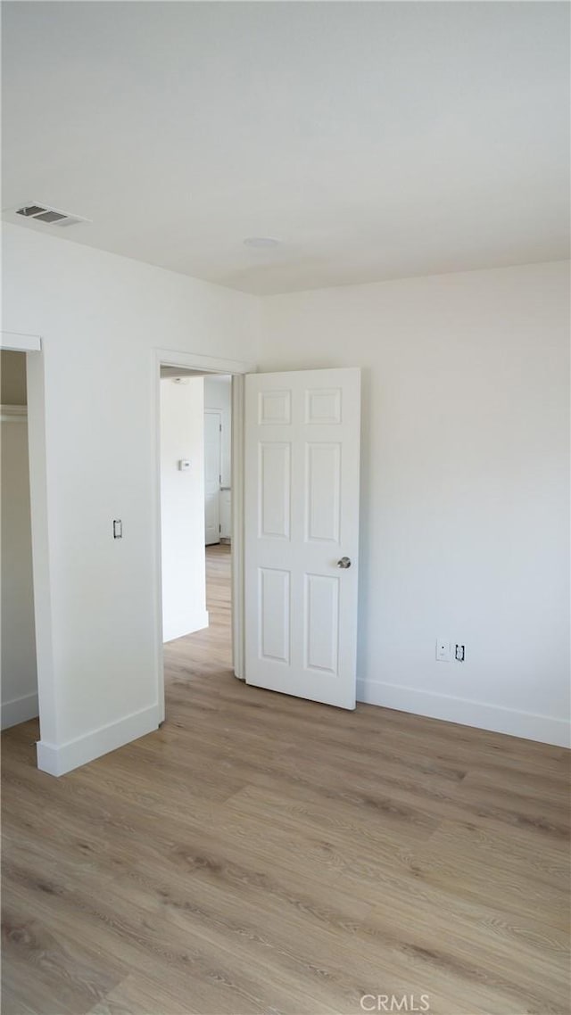 empty room featuring baseboards, visible vents, and light wood-style floors