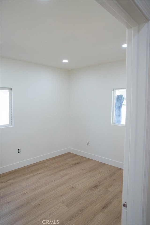 spare room with light wood-type flooring, recessed lighting, and baseboards