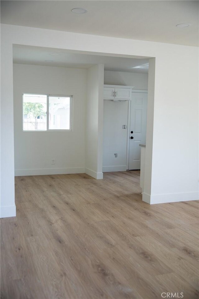 empty room with baseboards and light wood-type flooring