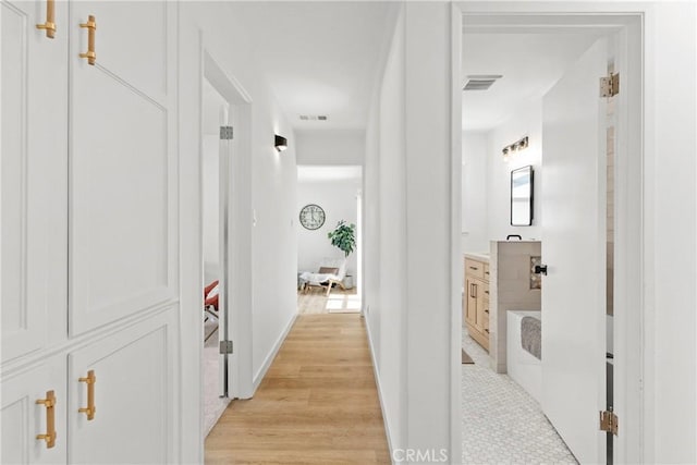 corridor featuring light wood-style floors, visible vents, and baseboards