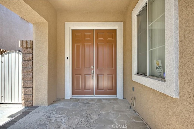 entrance to property with a gate and stucco siding