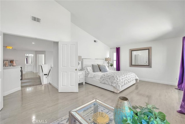 bedroom with high vaulted ceiling, visible vents, baseboards, and wood finished floors