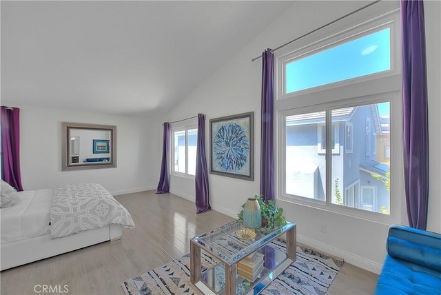 bedroom with light wood-style flooring, baseboards, and vaulted ceiling