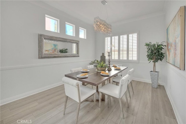 dining room with light wood finished floors, a notable chandelier, ornamental molding, and baseboards