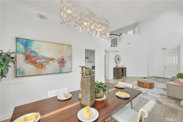 dining space with arched walkways, visible vents, a high ceiling, wood finished floors, and a notable chandelier