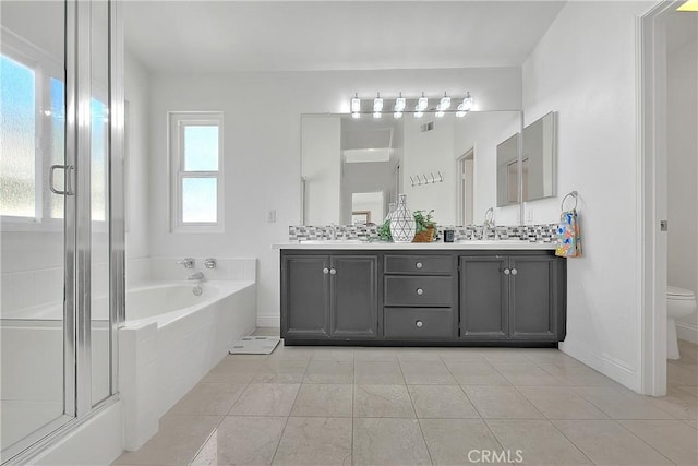 bathroom featuring double vanity, toilet, a shower stall, a bath, and a sink