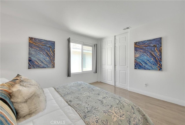 bedroom with visible vents, baseboards, and wood finished floors