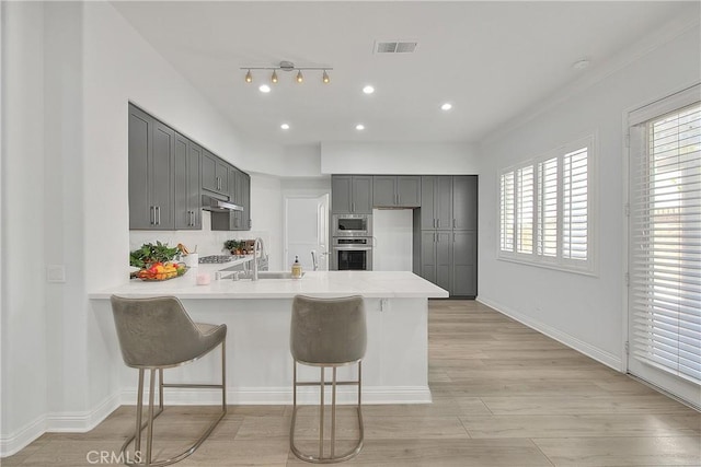 kitchen featuring a peninsula, a wealth of natural light, gray cabinetry, visible vents, and appliances with stainless steel finishes