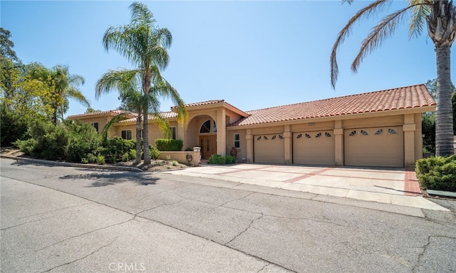 mediterranean / spanish home with a tiled roof, an attached garage, driveway, and stucco siding