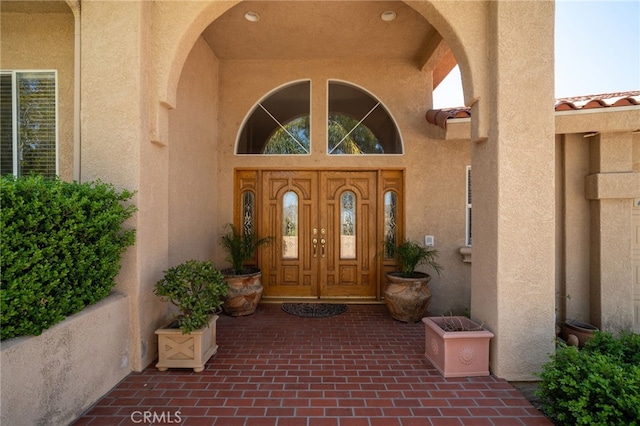 view of exterior entry featuring a tiled roof and stucco siding