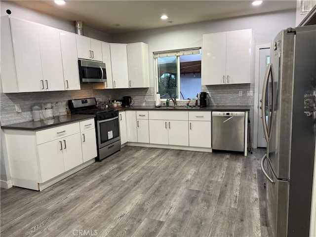 14615 Wyandotte St, Van Nuys, CA 91405 - kitchen with backsplash, dark countertops, stainless steel appliances, a sink, and wood finished floors