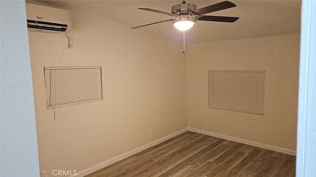 unfurnished room with a wall mounted AC, dark wood finished floors, baseboards, and ceiling fan