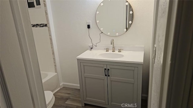 full bath featuring toilet, wood finished floors, vanity, and baseboards