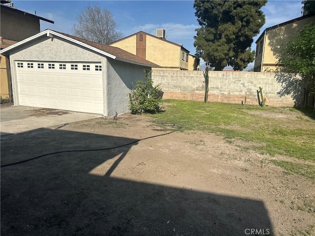 view of yard with central AC unit, driveway, fence, and an attached garage