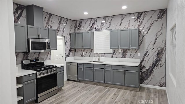 kitchen with light countertops, gray cabinetry, a sink, and stainless steel appliances