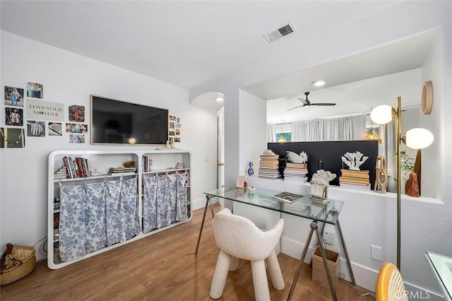 dining area with visible vents, a ceiling fan, arched walkways, and wood finished floors