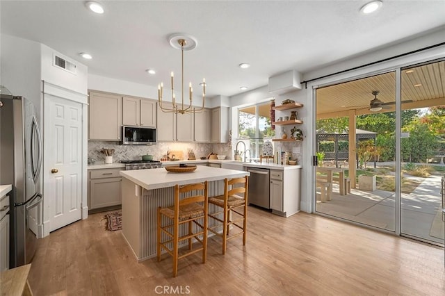 kitchen with visible vents, gray cabinets, appliances with stainless steel finishes, a sink, and backsplash