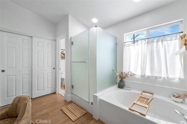 full bathroom with a stall shower, a garden tub, and wood finished floors