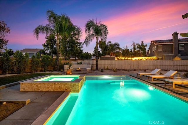 pool at dusk featuring a fenced in pool, an in ground hot tub, and a fenced backyard