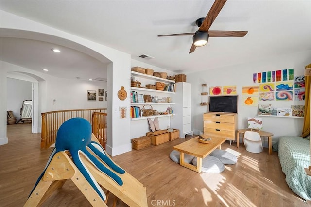 interior space featuring visible vents, ceiling fan, arched walkways, and wood finished floors