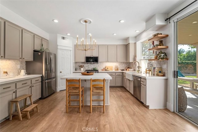 kitchen with light wood-style flooring, a center island, gray cabinetry, and stainless steel appliances