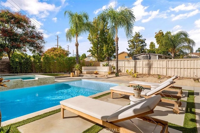 view of swimming pool with a fenced backyard, a pool with connected hot tub, and a patio area