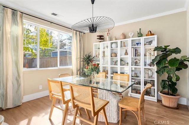dining area with crown molding, wood finished floors, baseboards, and visible vents