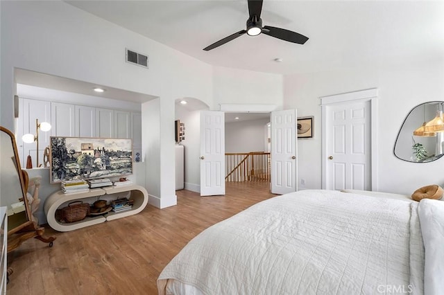 bedroom with visible vents, baseboards, arched walkways, ceiling fan, and wood finished floors
