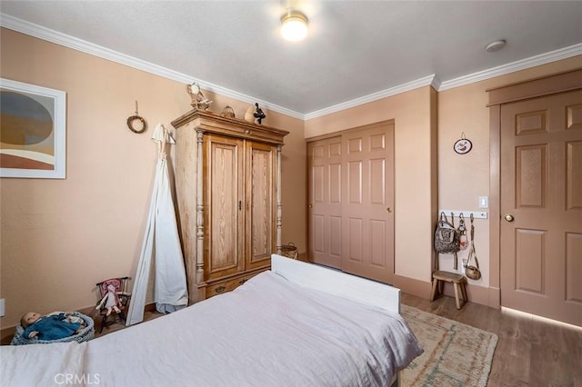 bedroom with ornamental molding and wood finished floors