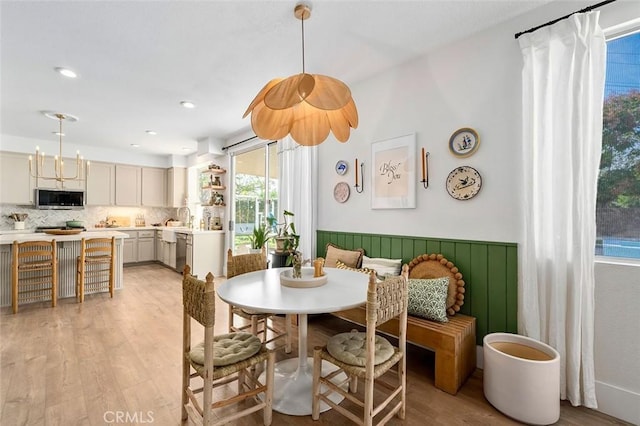 dining area with light wood-style flooring, a wainscoted wall, and recessed lighting