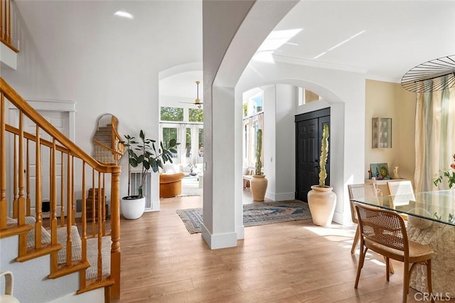 foyer entrance with arched walkways, wood finished floors, and stairs