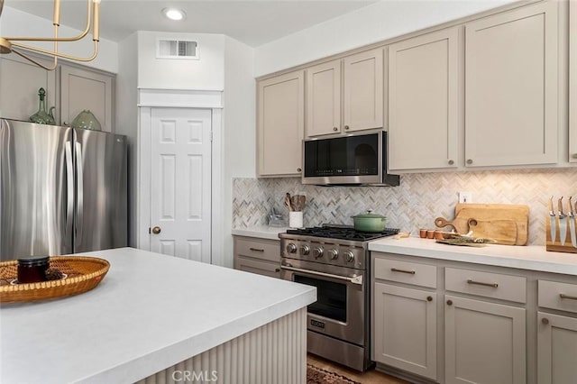 kitchen with visible vents, appliances with stainless steel finishes, light countertops, gray cabinetry, and backsplash
