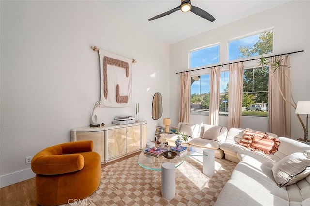 living area featuring ceiling fan, baseboards, and lofted ceiling