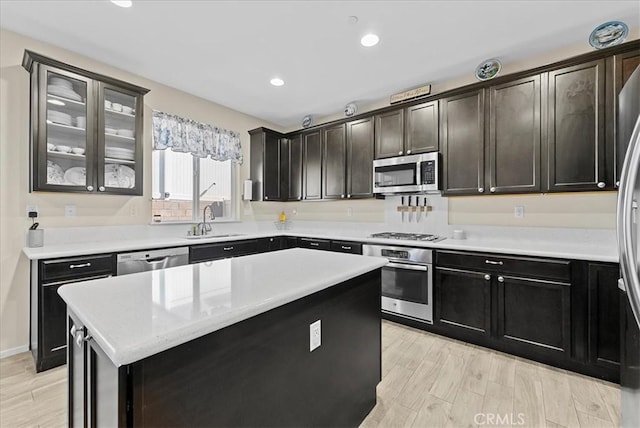 10969 Elkwood Cir, Riverside, CA 92503 - kitchen with appliances with stainless steel finishes, a sink, a kitchen island, recessed lighting, and glass insert cabinets